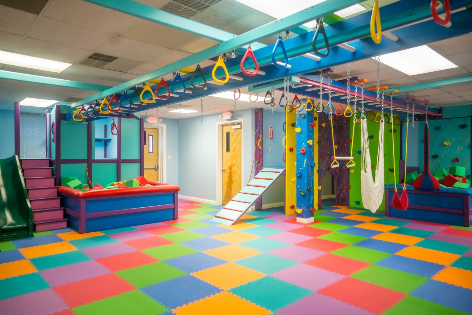 Fun Factory commercial sensory gym in Delaware with overhead ring track, climbing walls, and rainbow foam floor
