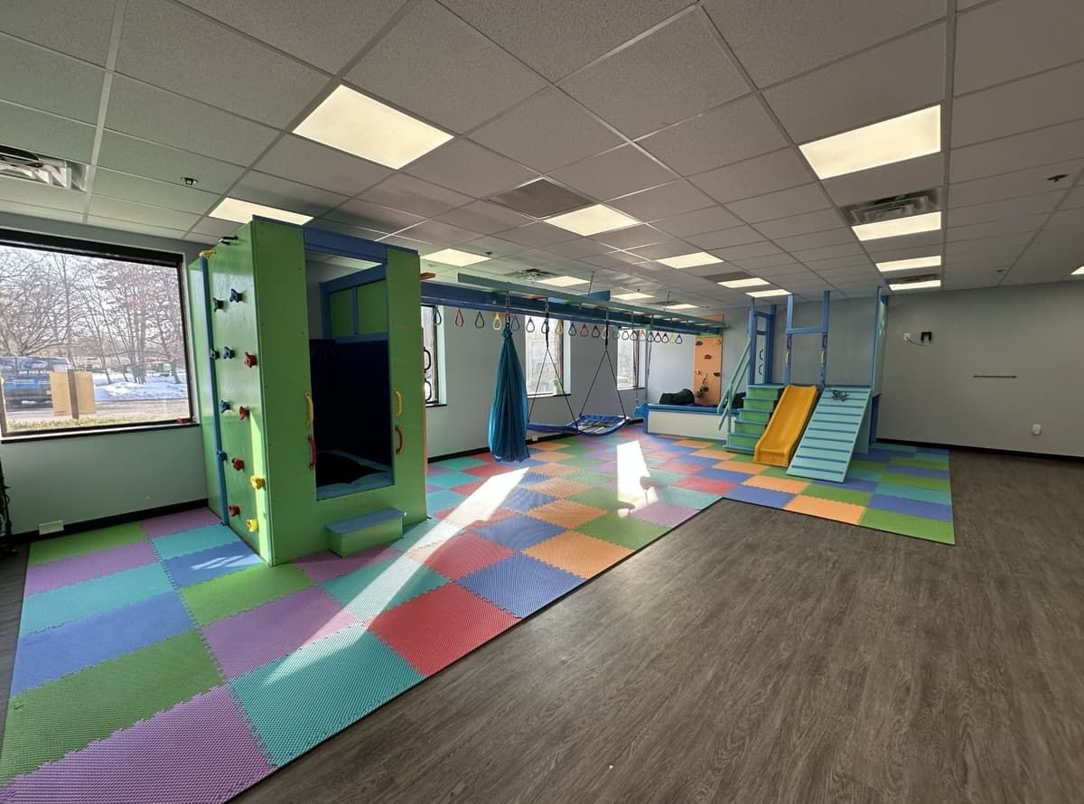 After: Fun Factory commercial sensory gym with green climbing structure, swings, and rainbow foam floor