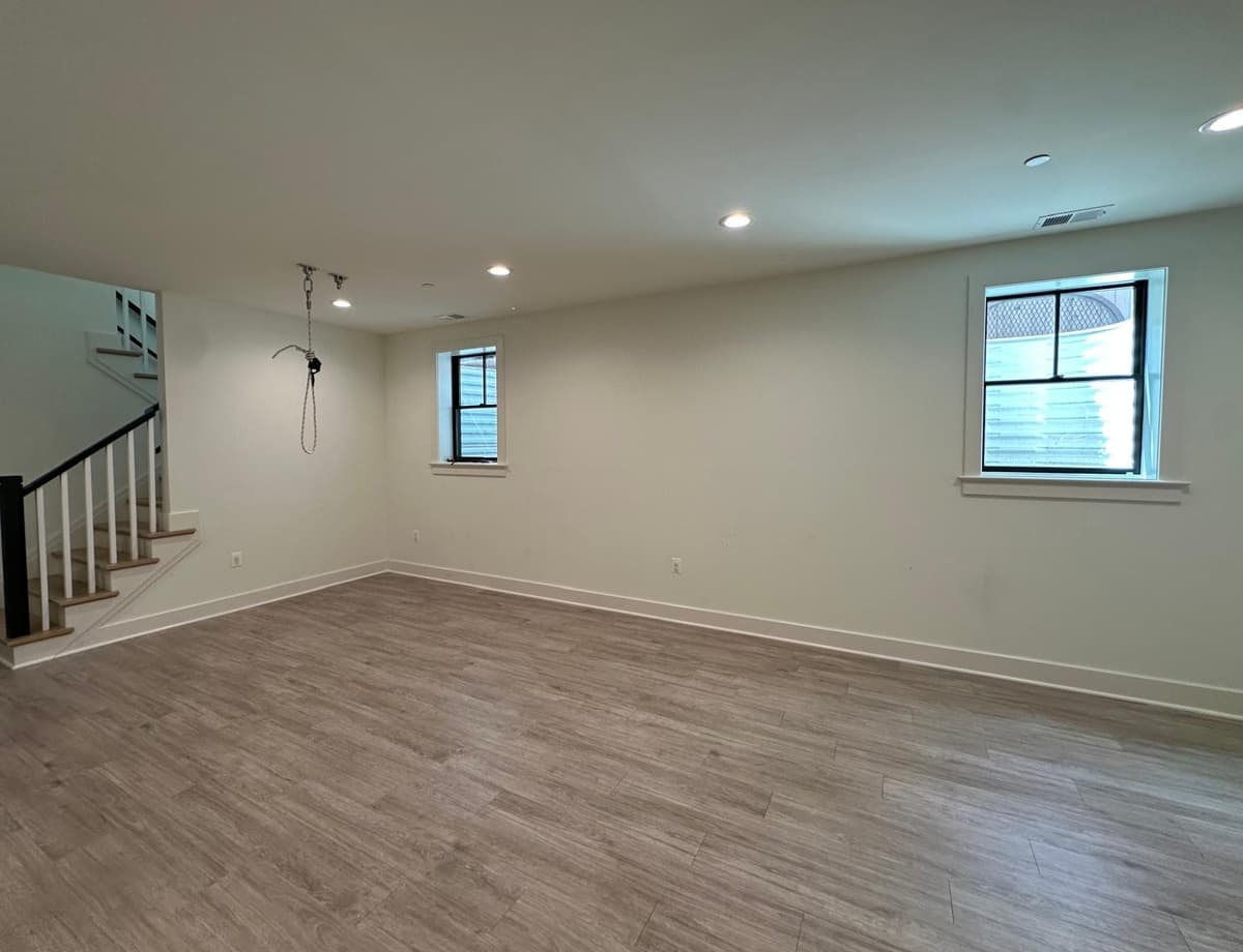 Before: empty finished basement with wood floor and staircase, ready for a home sensory gym