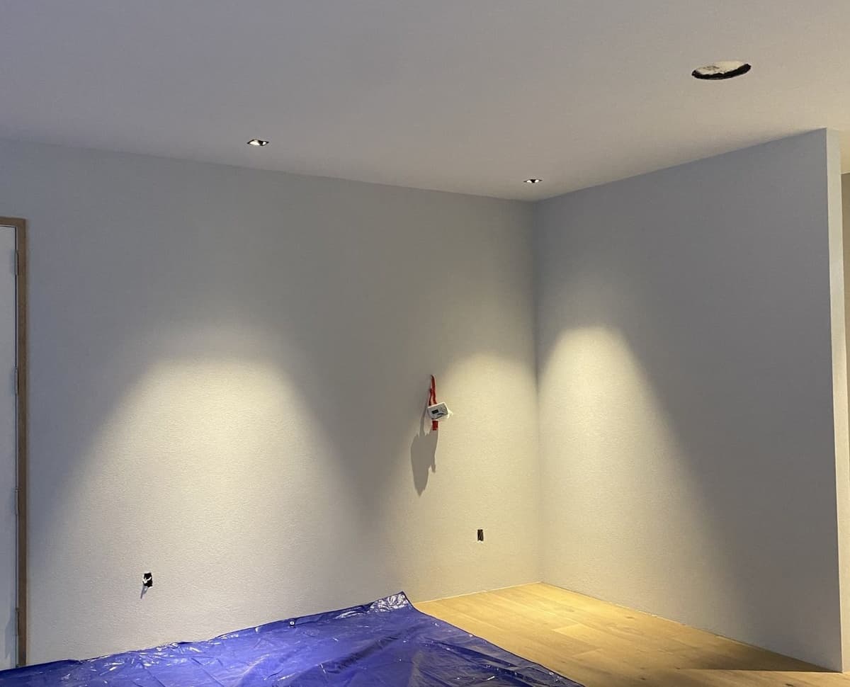 Before: bare corner of a home with white walls and unfinished floor before the sensory gym build