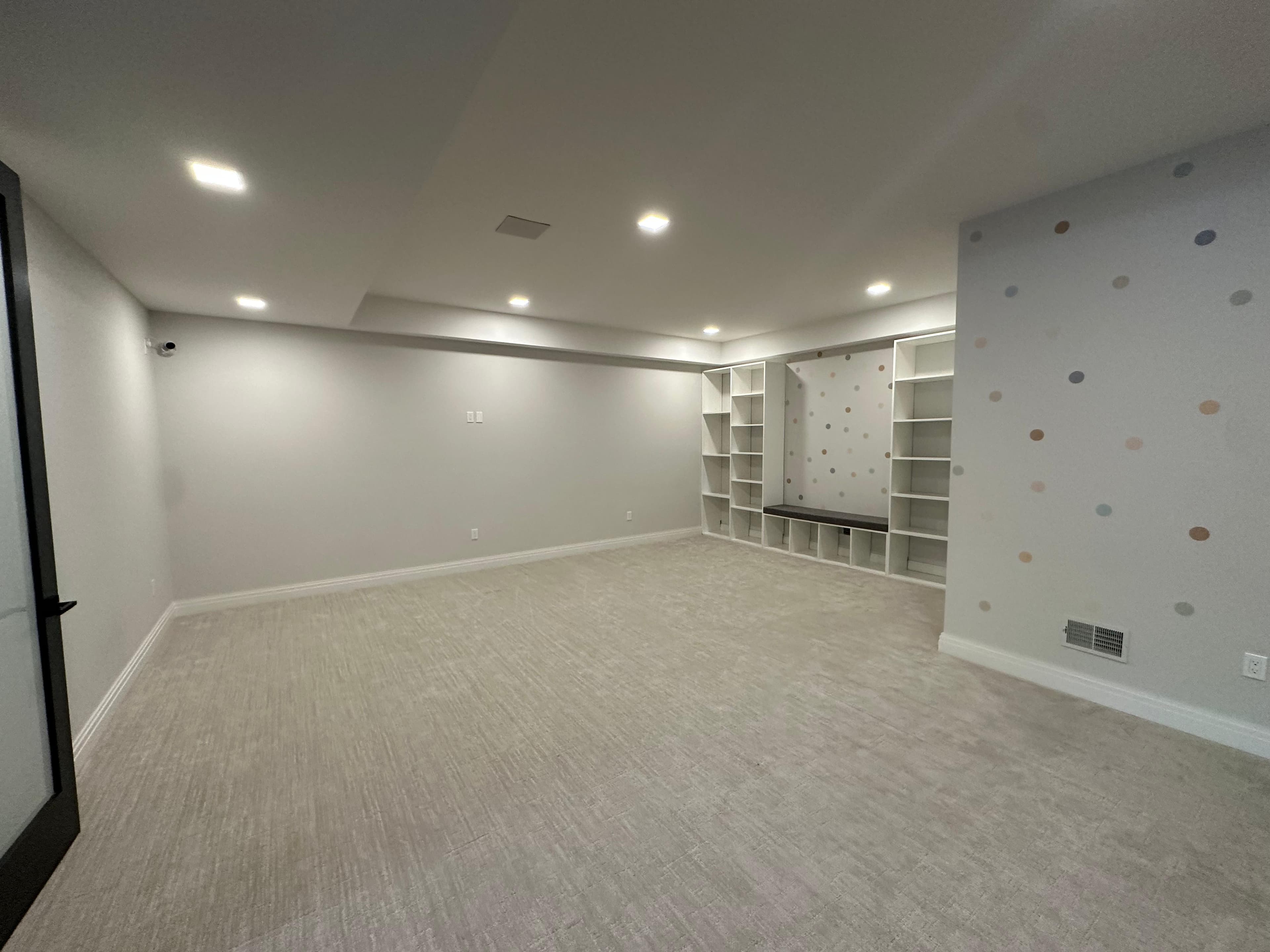 Before: empty carpeted basement with built-in shelving before the home sensory gym install
