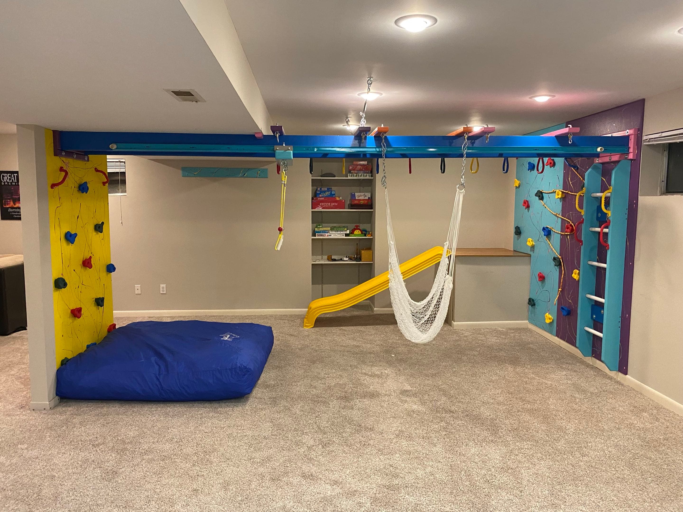 Home activity station with overhead swing track, white net swing, yellow slide, and blue crash pad